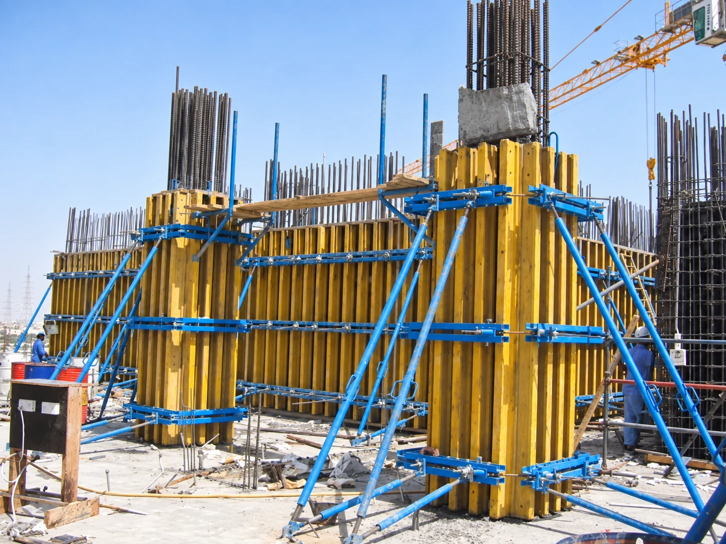 Vertical yellow formwork beams, blue steel walers and stabilizing props