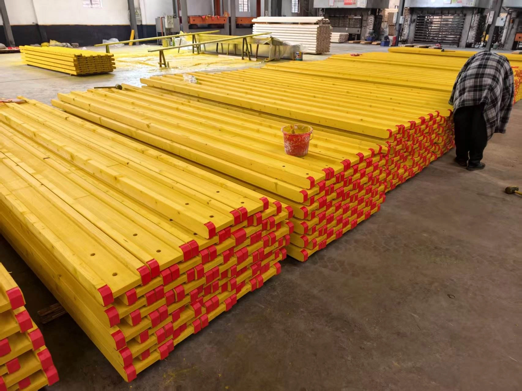 Yellow coated timber beams with red ends in a workshop