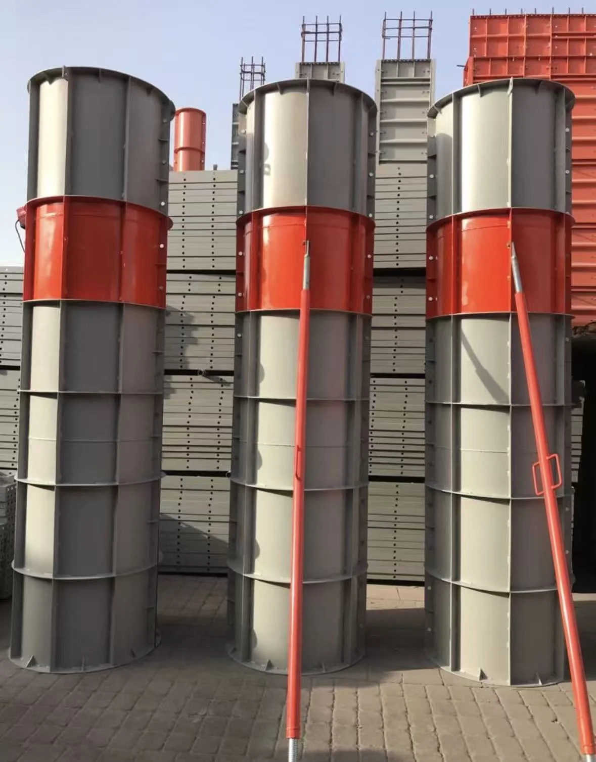 Assembled circular column steel formwork sections in red and grey finishes