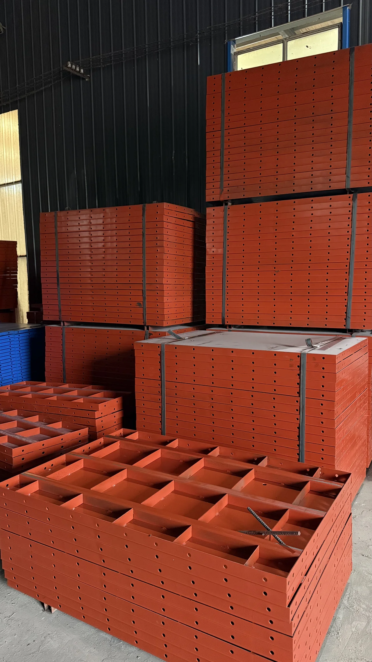 Stacks of finished red flat steel formwork panels in factory inventory