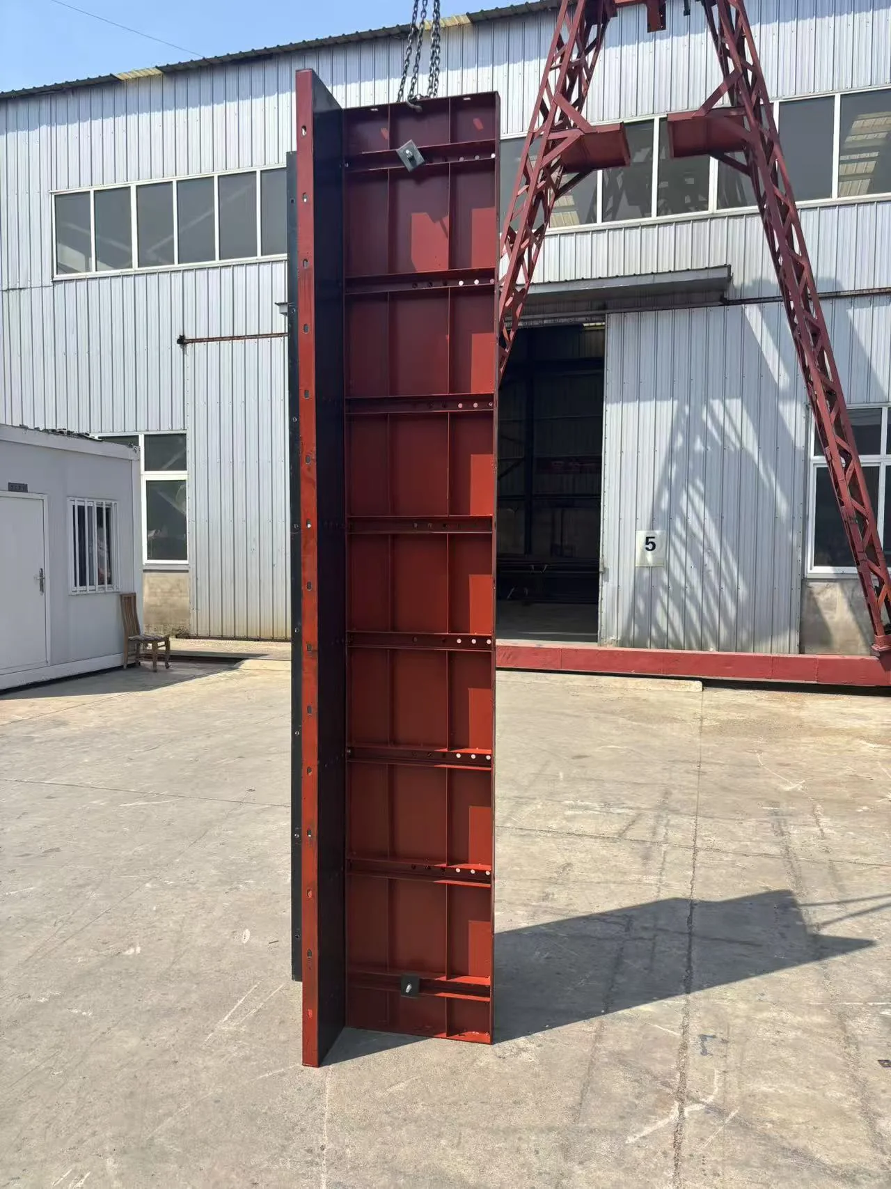 Single tall flat steel formwork panel being handled outside the workshop