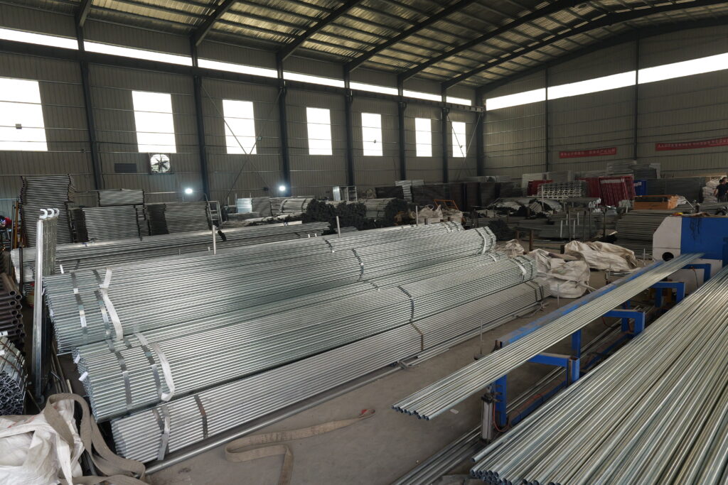Large inventory of bundled premium steel pipes and custom construction scaffolding parts inside factory warehouse