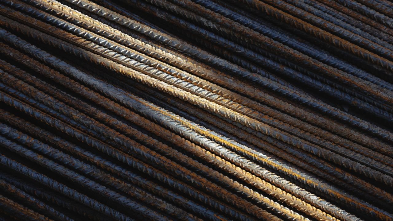 Detailed view of intersecting steel rebars showing texture and rust patterns under sunlight.