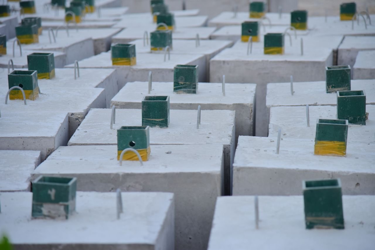 Close-up of concrete foundation blocks with embedded metal rods, ready for construction.